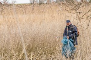 Man zoekt afval in de natuur. Boswachters vinden steeds vaker gedumpt afval.