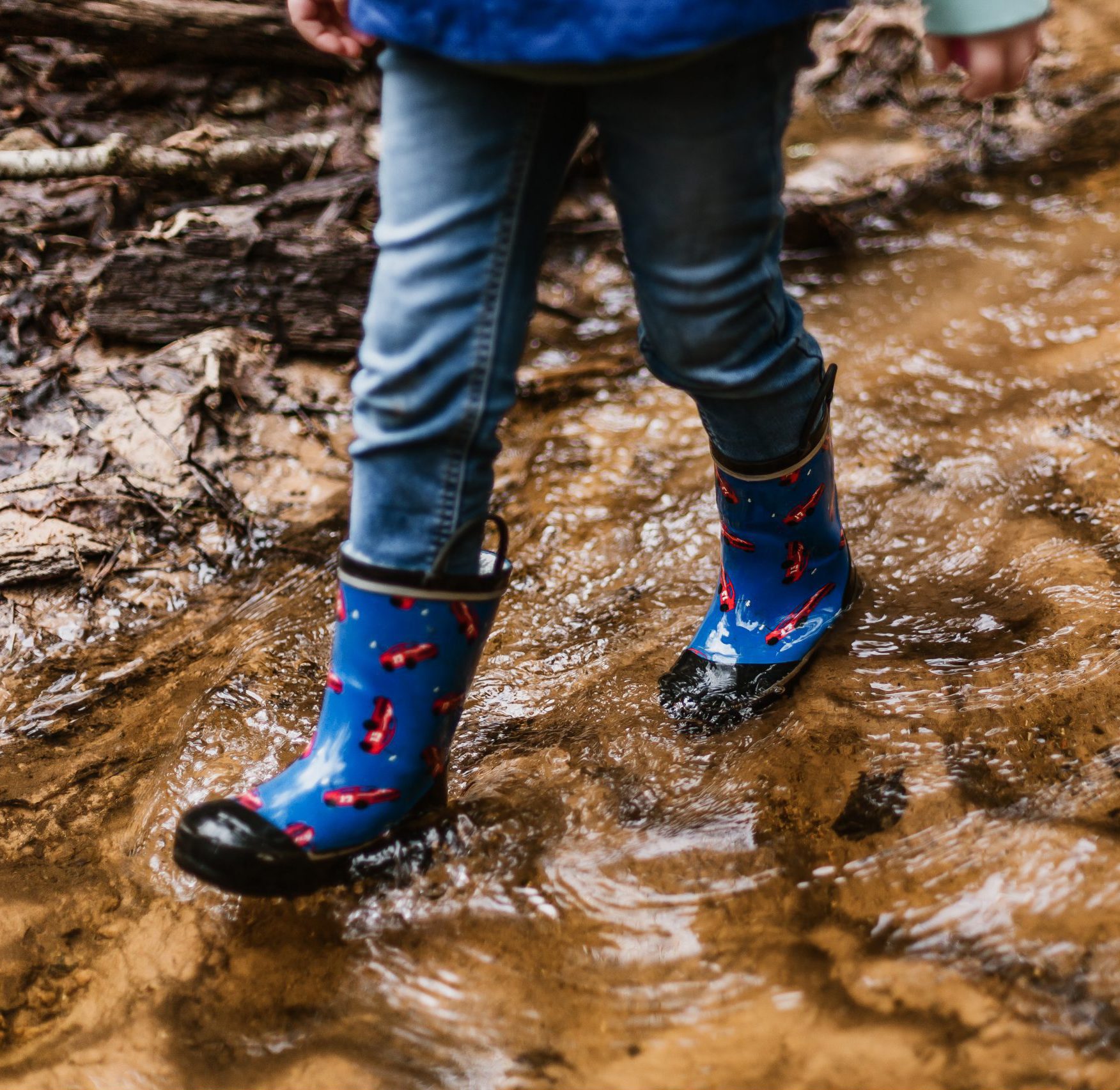 kind loopt met laarzen door water