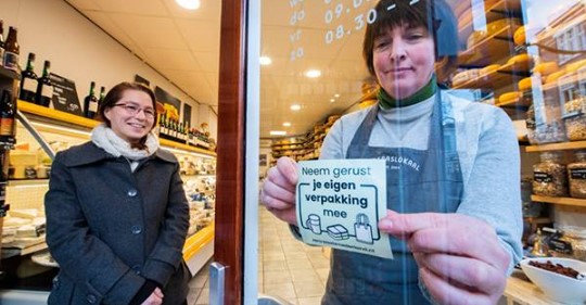 vrouw plakt zero waste sticker op ruit