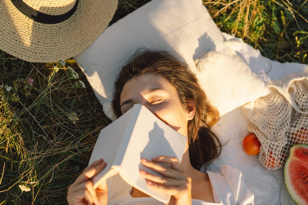 vrouw leest boek op grasveld