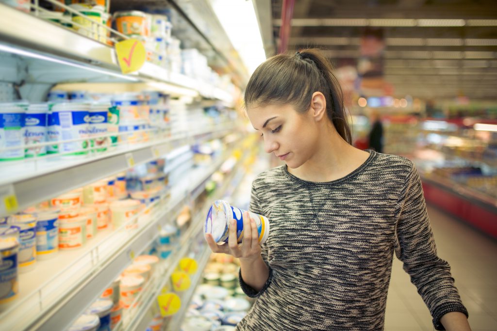 vrouw kijkt naar product in supermarkt