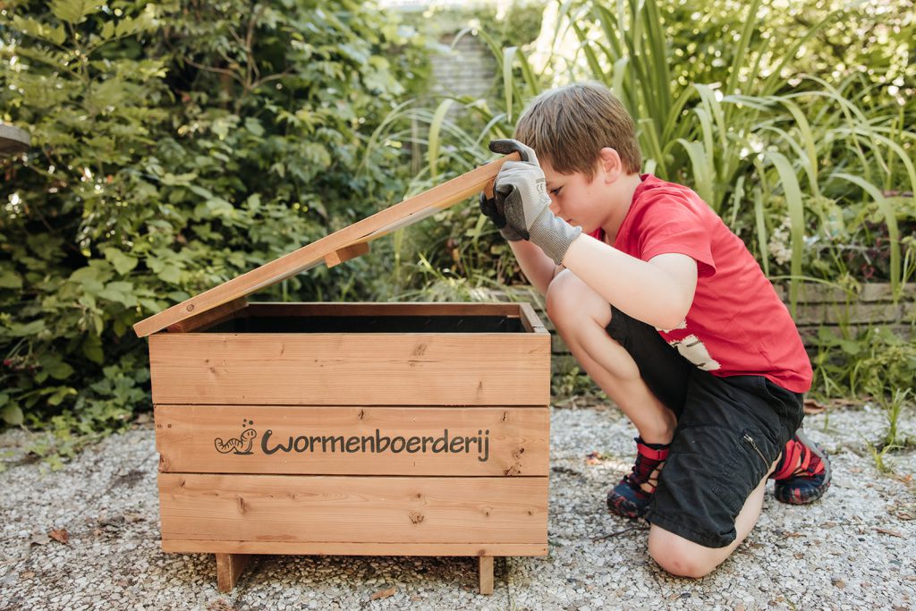 jongetje kjikt in wormenhotel in tuin